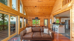 Een ruim houten cabin interieur met een grote leren bank, een eethoek en een keuken.