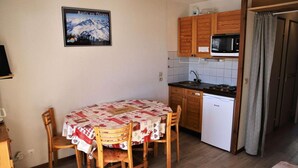 A compact kitchen with wooden cabinets, a microwave, and a small sink. - View open, balcony, parking, tv, ski locker, 27m², Auris en Oisans (Auris)