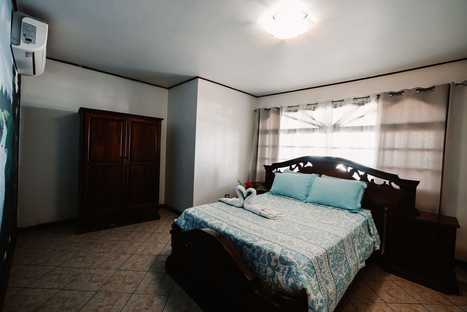Et soveværelse med seng, garderobe, natbord og loftlampe.