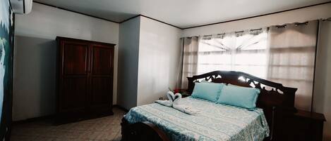 Et soveværelse med seng, garderobe, natbord og loftlampe.