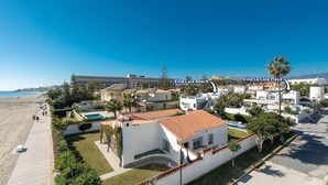 Un complexe de villas en bord de mer, doté d’une piscine, de palmiers et offrant une vue dégagée sur la plage.