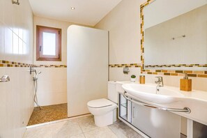 Une salle de bain équipée d’une douche, de toilettes, d’un lavabo et d’un grand miroir.