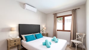 Ein ordentlich eingerichtetes Schlafzimmer mit Bett, Nachttischen, einem Sessel und einem Fenster mit Vorhängen.