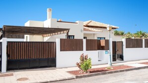 Ein modernes Haus mit weißer Fassade, einem Ziegeldach und einem Holzzaun.