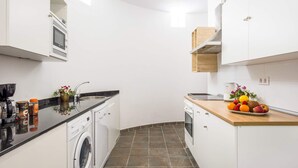 A compact kitchen with a washing machine, a coffee machine, and a fruit bowl on the counter. - Villa Corito Cinco by Villa Plus (Playa Blanca)