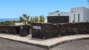 A stone wall with a sign reading "CASA CORITTO" and a modern white building with a flat roof. - Villa Corito Cinco by Villa Plus (Playa Blanca)