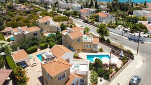 A residential area with houses, a swimming pool, and a view of the sea. - Villa Camelia by Villa Plus (Peyia)