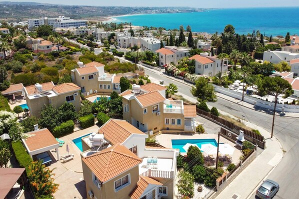 A residential area with houses, a swimming pool, and a view of the sea.