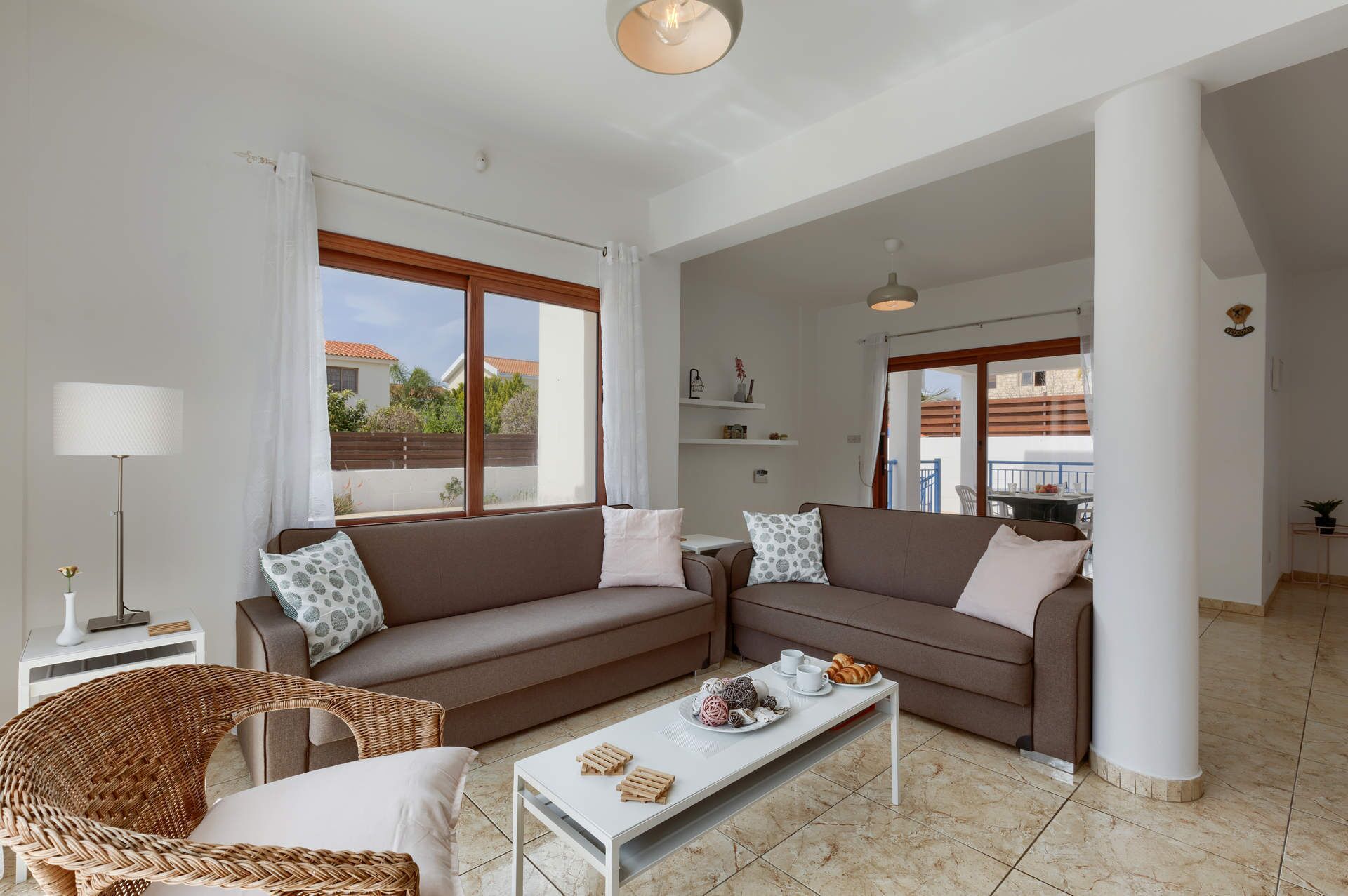 A spacious living area with two sofas, a coffee table, and a wicker chair.