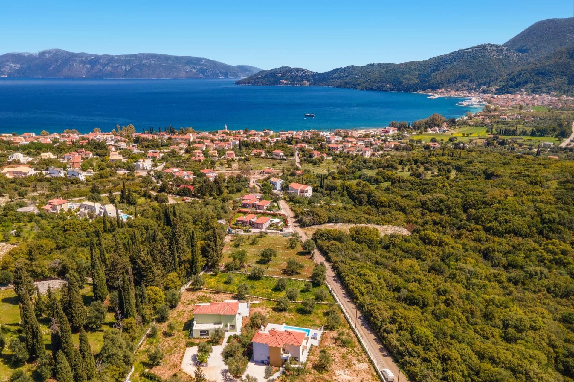 An aerial view of a coastal town with houses, a road, and a body of water.