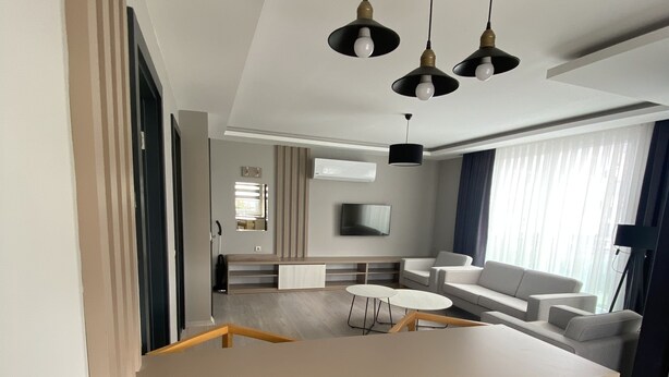 Une cuisine moderne dotée d’un îlot central, de chaises en bois et de luminaires suspendus.