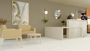 Un espace d’accueil moderne comprenant un canapé, des fauteuils, un comptoir de réception et un grand tableau abstrait.