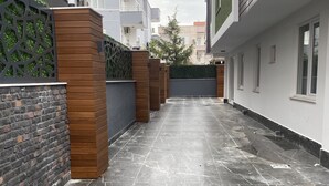 Une cour intérieure urbaine moderne, dotée d’un sol carrelé, de murs en bois et en briques, et d’un portail en métal.