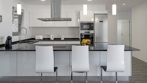 Una cocina moderna con una isla central, electrodomésticos de acero inoxidable e iluminación colgante.