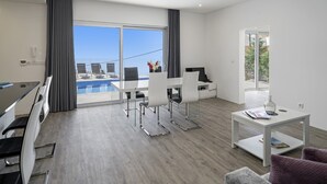 Una habitación de hotel moderna con balcón, zona de comedor y espacio de trabajo.