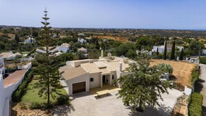 A modern house with a tiled roof, surrounded by greenery and a clear view of the sea. - Villa Campos by Villa Plus (Guia)