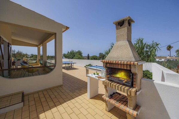An outdoor patio with a brick oven, seating area, and a view of the landscape.