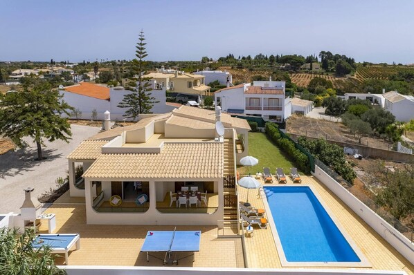 A residential property with a swimming pool, outdoor seating, and a view of the surrounding landscape.