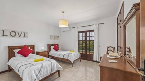 A bedroom with two beds, a dresser, a mirror, and a window with curtains. - Villa Campos by Villa Plus (Guia)