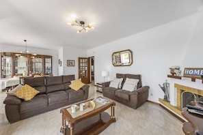 A spacious living room with two sofas, a coffee table, and a fireplace.