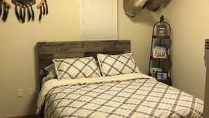 A bedroom with a bed, a wall-mounted deer head, a ceiling fan, and a shelf with books and a picture frame. - Outdoorsman Paradise- 1/2 mile from Lake Oahe (Pierre)