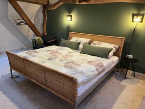A bed with a woven headboard, two wall-mounted lights, and a small side table.