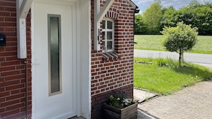 A brick house with a white door and a small window. - Fehnhaus - cozy vacation apartment with house character (Großefehn)
