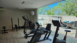A gym with various exercise equipment, including treadmills and weight machines, with a view of the street outside. - Golden Lake Residence (Arraial do Cabo)