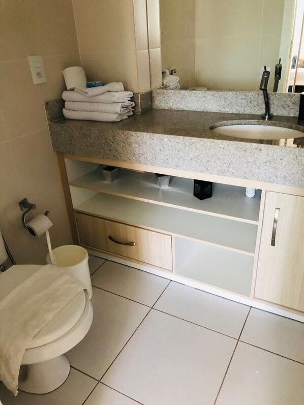 Une salle de bain comprenant des toilettes, un lavabo et des meubles de rangement.