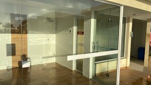 A modern building entrance with a glass door leading to a sauna area. - Golden Lake Residence (Arraial do Cabo)