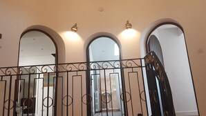 Una escala amb barana de ferro forjat que condueix a un espai intermèdia amb tres portals d'arc.