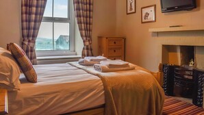 A bedroom with a bed, a dresser, a television, and a fireplace. - Bondcroft Farm Cottage (Eastby, near Skipton)
