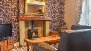 A living room with a fireplace, a television, and a sofa. - Bondcroft Farm Cottage (Eastby, near Skipton)