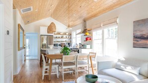 A modern kitchen with white cabinets, wooden countertops, and a hanging light fixture. - Church St Collection - 106 (Fairhope)