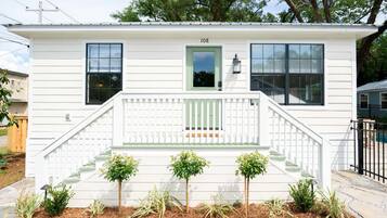 A single-story house with a front porch, a green door, and the number 108 on the wall.