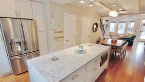 A modern kitchen with a marble countertop, stainless steel appliances, and a dining area with a table and chairs. - The Hip Strip - Stroll to Columbia Heights (Washington)