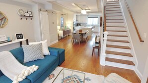 A spacious living room with a blue sofa, a dining area, and a kitchen in the background. - The Hip Strip - Stroll to Columbia Heights (Washington)