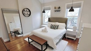 A modern bedroom with a large bed, bedside tables, a mirror, and a bench. - The Hip Strip - Stroll to Columbia Heights (Washington)