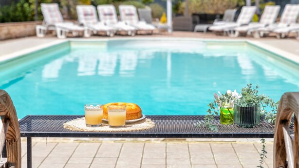 Area piscina con lettini, un tavolino con bevande e una piccola pianta.