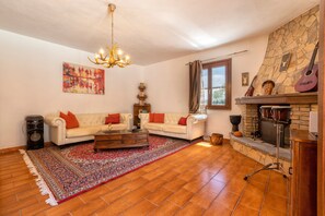 A living room with a fireplace, a chandelier, a sofa set, and a large rug. - Villa 'Matian' with Private Pool, Wi-Fi and Air Conditioning (marina di sorso)