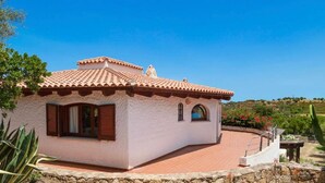 A small, single-story building with a tiled roof, a stone foundation, and a paved patio area. - Villa Runcina with sea view, Wi-Fi and private pool (San Teodoro)