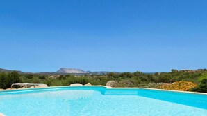 A clear blue swimming pool with a view of a mountain in the background. - Villa Runcina with sea view, Wi-Fi and private pool (San Teodoro)