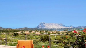 A balcony with a wicker chair, a railing, and a view of a mountain and a body of water. - Villa Runcina with sea view, Wi-Fi and private pool (San Teodoro)