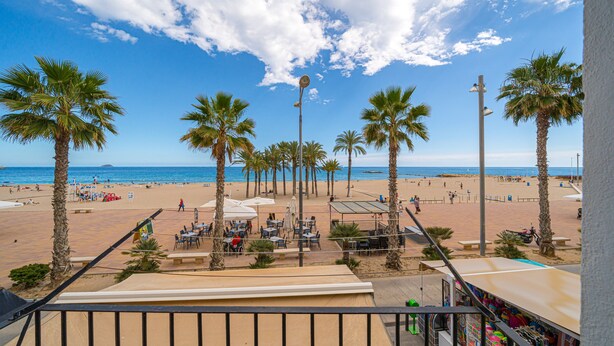Uitzicht op een strand met palmbomen, een zandstrand en enkele parasols.