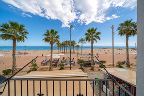 Une vue sur la plage, avec des palmiers, une plage de sable et quelques parasols.
