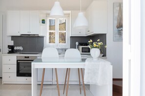 Een moderne keuken met witte kasten, een glazen tafel en hanglampen.