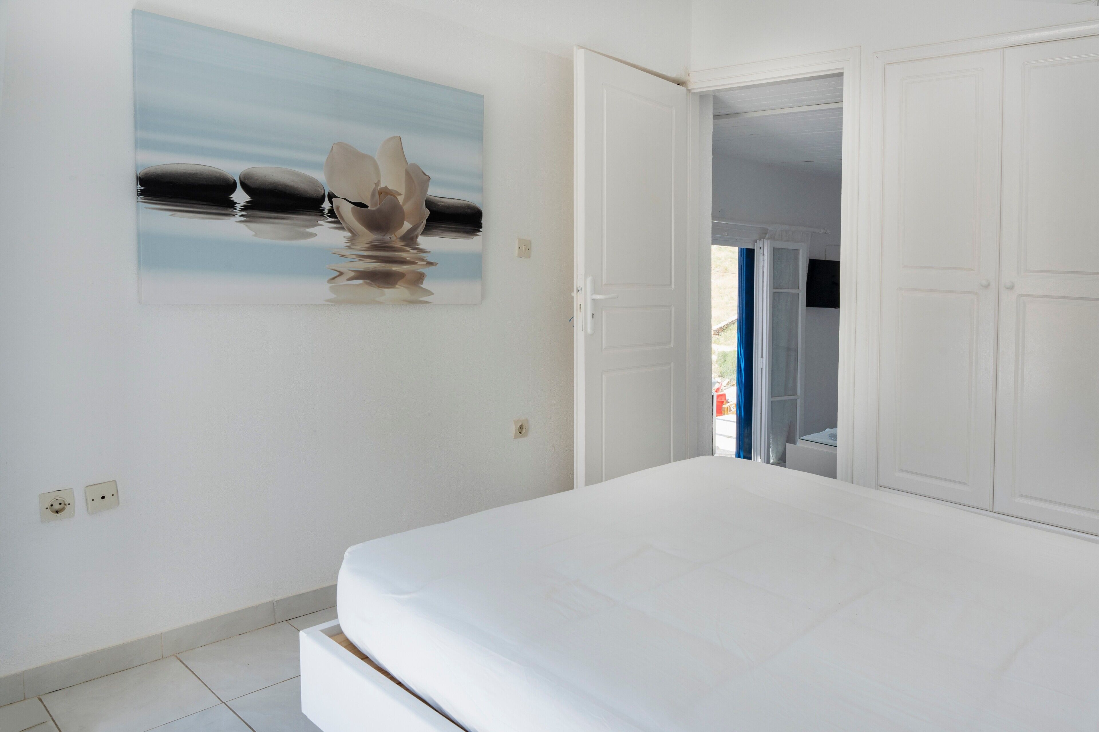 A bedroom with a bed, a painting, and a wardrobe.