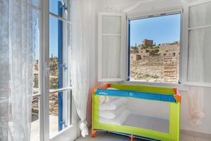 Una habitación con ventana, una cuna para bebé y vistas a ruinas antiguas.