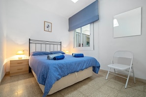 A bedroom with a bed, bedside table, lamp, window, and a chair. - Apartment 'Vista Mar' with Sea View, Wi-Fi and Air Conditioning (l'ampolla)