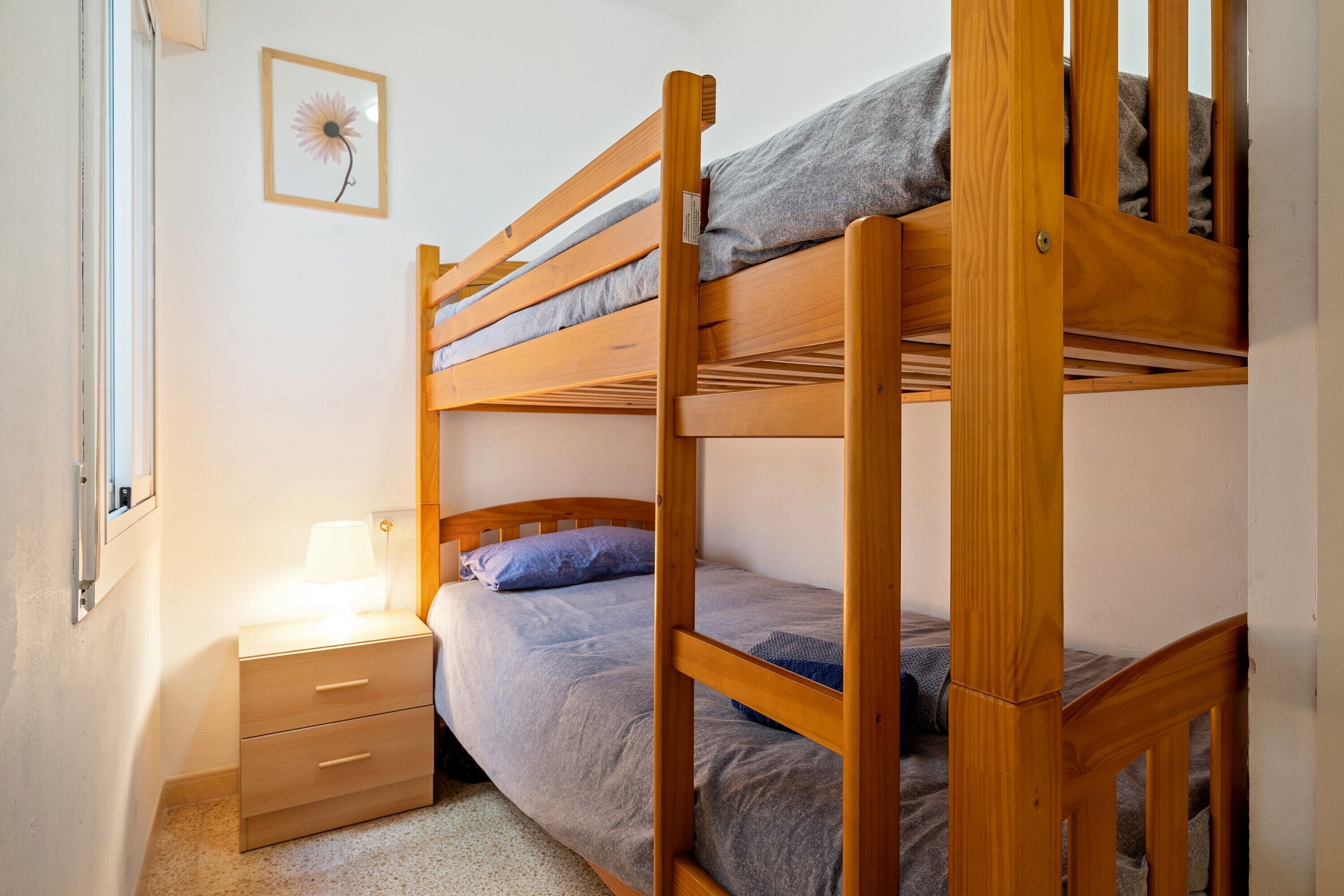 Camera con letto a castello, un comodino e una lampada.